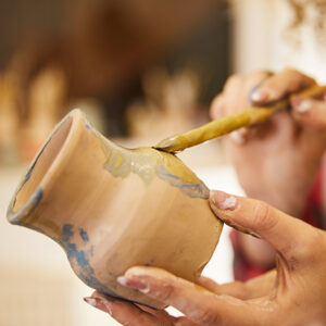 Close up, girl paints a vase before baking